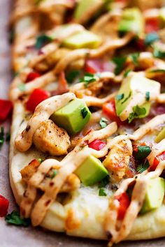 a flatbread pizza with chicken, avocado and tomatoes on it's side