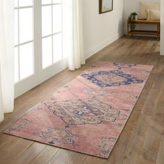 a large pink rug on the floor in front of a window