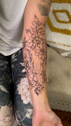 a woman's arm with flowers and an elephant tattoo on the left side of her arm