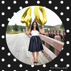 a woman holding two gold balloons in front of her face and standing on a bridge