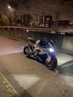 the motorcycle is parked on the side of the road near some concrete barriers at night