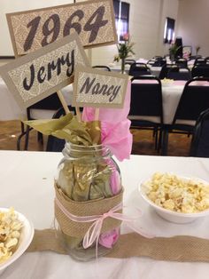 a jar filled with popcorn sitting on top of a table next to bowls of food