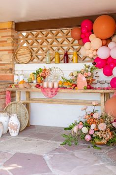 a party with balloons, flowers and other decorations on the wall in front of a table