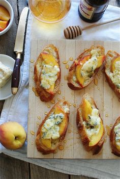 several pieces of bread with cheese and fruit on them sitting on a wooden cutting board