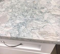 a marble counter top in a kitchen with stainless steel handles and knobs on the drawer