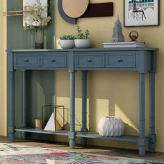 a blue console table with two drawers and one drawer on the top, in front of a yellow wall