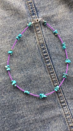 a pink and blue beaded necklace on a pair of jeans