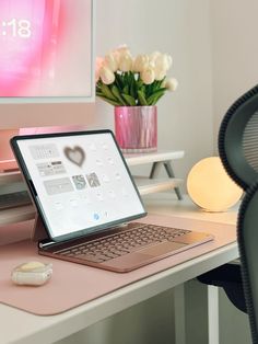 an open laptop computer sitting on top of a desk next to a vase with flowers