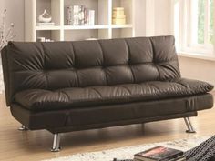 a brown leather futon sofa sitting on top of a hard wood floor next to a book shelf