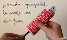 a hand holding a red and white tube with writing on the wall next to it