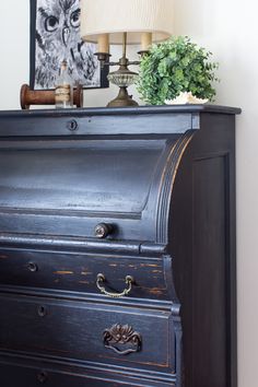 an old black dresser with a lamp on top