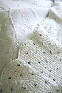 an unmade bed with white sheets and blue flowers on it's coverlet