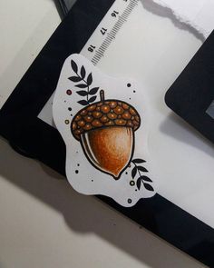 an acorn sticker sitting on top of a white table next to a black frame