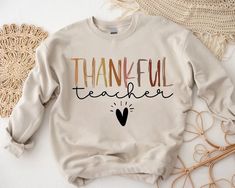 "Thankful Teacher Sweatshirt,Teacher Thanksgiving Shirt,Fall Gift For Teacher,Teacher Shirt,Thankful Sweatshirt,Teacher Team Sweatshirt 🎁 Enjoy your shopping ! Need custom made shirts? Don't hesitate to message us! Thanks for your support! CustomShirtsZone_ Family ----- How To Order ----- 1-) Please, check and review all the photos. 2-) Select Your Size and Color from drop down menus. 3-) Click add to cart. You can go back to add more sweatshirts. 4-) Click \"Proceed to check out\" to purchase your order. 5-) When you check out, you can add a note to seller for any request. SIZING We are using Unisex sizing sweatshirts for a casual and relaxed fit. That means they run slightly larger than typical women's one and slightly smaller than typical men's ones. ✔ Please refer to the size chart st Enter His Gates With Thanksgiving, Teacher Thanksgiving, Christian Thanksgiving, Thankful Sweatshirt, Teachers Thanksgiving, Christian Fall, Bible Verse Tees, Thanksgiving Sweatshirt, Team Sweatshirts