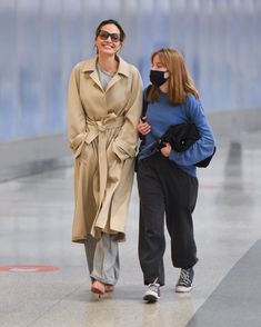 two women walking down the street wearing face masks