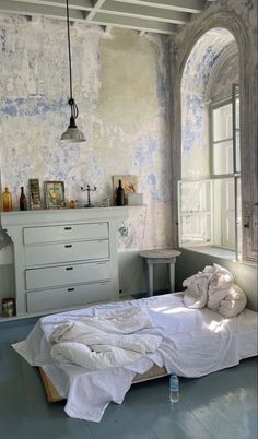 an empty bed with white sheets and pillows in a room that has been painted blue