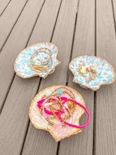 three pieces of jewelry sitting on top of a wooden table