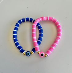 two bracelets with evil eyes on them sitting on a white counter top next to each other