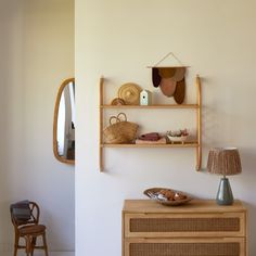 a wooden shelf with baskets on it next to a mirror and lamp in a room