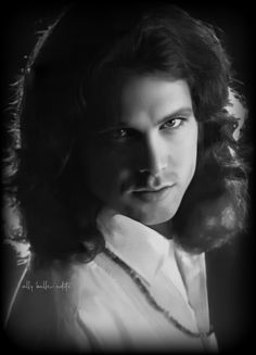 a black and white photo of a woman with curly hair wearing a collared shirt