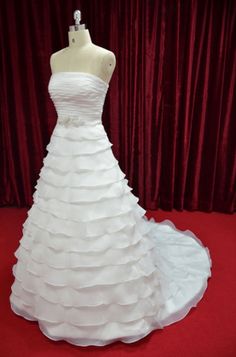 a white wedding dress on display in front of a red curtain