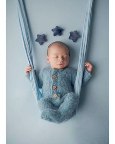 a baby sleeping in a blue knitted outfit with stars hanging from it's sides