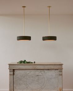 two lights hanging over a table in a room with white walls and flooring,