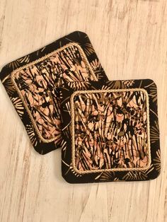 two square coasters with black and pink designs