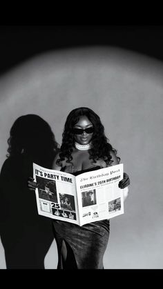 a woman is reading a newspaper while standing in front of a dark shadow on the wall