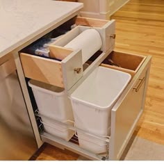 an open drawer in the middle of a kitchen with toilet paper and other items inside