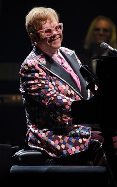 an older man in a suit and tie sitting at a piano