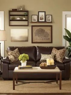 a living room with brown leather furniture and pictures on the wall above it's coffee table