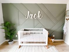 a baby's room with a white crib and green accent wall