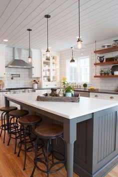 a kitchen island with four stools in front of it