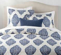 a bed with blue and white comforters on top of it, next to a wall