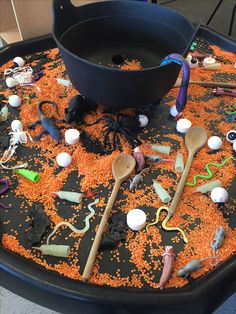 a black tray filled with lots of toys and spoons on top of an orange table