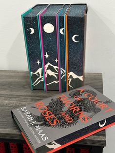 three books are stacked on top of each other in front of the moon and stars