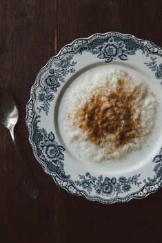 a plate with some kind of food on it next to a spoon and fork that is sitting on a wooden table