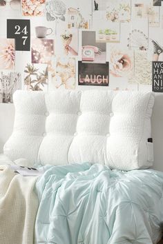 a bed with pillows and blankets on it in front of a wall full of pictures