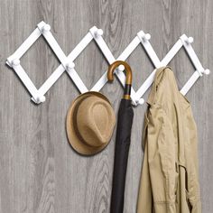 an umbrella, hat and coat hanger on a wooden floor next to a jacket rack