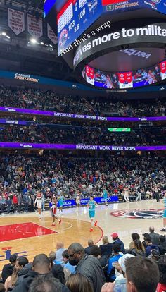 a basketball game is being played in an arena with people sitting on the floor watching