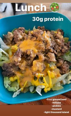 a blue bowl filled with lettuce and meat covered in cheese on top of it