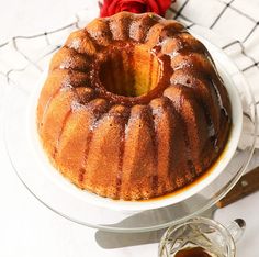 a bundt cake sitting on top of a white plate next to a red rose