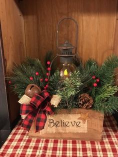 a wooden box filled with pine cones and evergreens on top of a tablecloth covered table