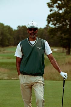 a man holding a golf club on top of a green field