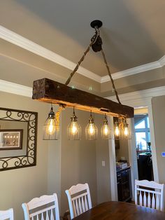 a wooden beam is suspended from the ceiling over a dining room table with white chairs