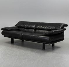 a black leather couch sitting on top of a white floor