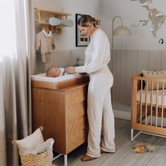 a woman standing next to a baby in a crib