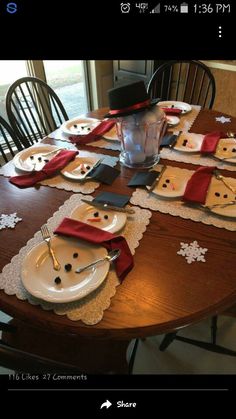 a wooden table topped with white plates covered in snowman napkins and place mats