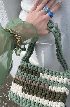 a woman's hand holding onto a green and white purse